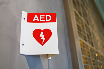 Automated External Defibrillator (AED) sign in a building for the prevention of heart attacks patient. Soft focus image. - obrazy, fototapety, plakaty