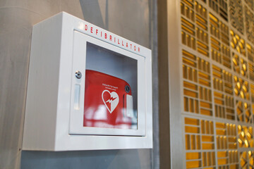 An automated external defibrillator box in a commercial building. It is a lightweight, portable device that delivers an electric shock through the chest to the heart. - obrazy, fototapety, plakaty
