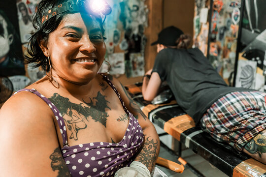 Latin tattoo artist with a lamp in front of her smiling in front of the camera in her studio in Managua Nicaragua