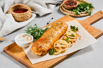 Meat pie with greens and onion on wood plate. Eastern food - beef pie with sesame. Eastern pastry with Minced meat.