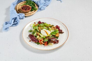 Green salad with sliced roast beef and pachot egg. Roast beef salad with vegetables and egg on concrete background in minimal style. Aesthetic composition with meat salad, textile and spices.