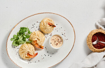 Steamed dumplings shrimp in asian style on white concrete background. Prawn dim sum with sauce on...