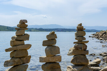 Rock cairn the art of stone balancing on a stone near a blue water flowing lake. Sunny day on the lake. A mood of calm and harmony with nature.
