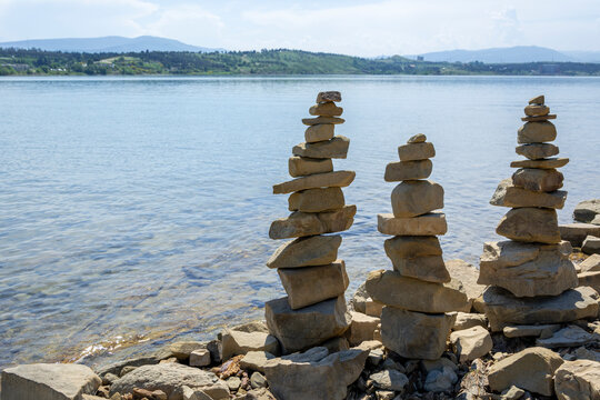 Rock cairn the art of stone balancing on a stone near a blue water flowing lake. Sunny day on the lake. A mood of calm and harmony with nature.