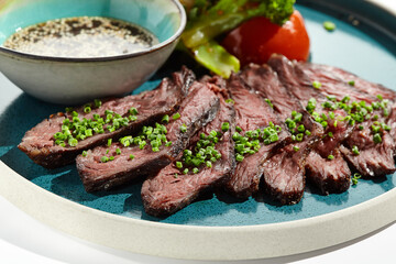 Roast beef with vegetables and sauce on trendy plate. Sliced meat steak roast grill with tomatoes and broccoli isolated on white table. Angus roast beef in healthy style for restaurant.