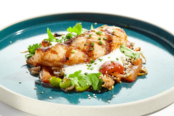 Healthy food - baked salmon steak with tomato salad and white sauce. Roast salmon with vegetables on contemporary plate in asian style. Restaurant dish - salmon filet with hard shadow.