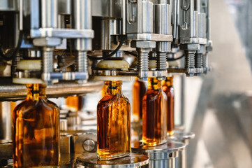 Conveyor carries glass bottles of luxury cognac in workshop