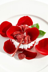 Dessert red velvet in contemporary style with raspberry and petals roses. Romantic cake - red velvet for st. valentine's day, wedding. Luxury pastry on white plate concept. Restaurant luxury dessert.