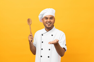 Young handsome asian man chef in uniform with hat holding ladle utensils cooking in the kitchen...