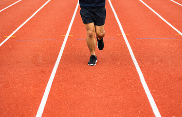 Close up legs Young chinese man wearing sportswear running on track at sport stadium. Fit man...