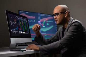 Investor businessman analyzing a graphic of a stock cryptocurrency exchange chart and looks at computer monitor. Financial analyst working with real-time exchange rate diagram. Investment concept