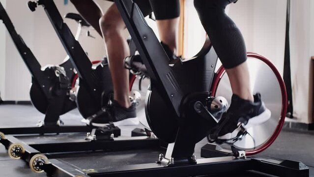 Slow motion video of feet cycling on stationary bike at an indoor fitness gym