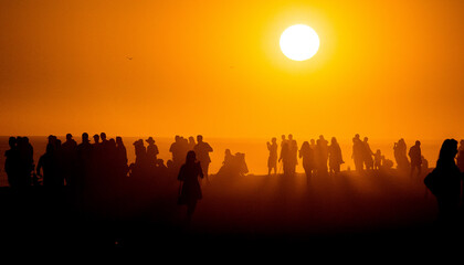 Silhouette of people looking toward the sun on a misty beach
