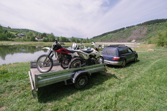 Auto trailer with motocross motorcycles near the river on  summer day