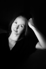 Fototapeta premium Black and white photo of an attractive woman. A large portrait on a dark background. Vertical photo.