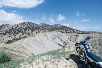 Dirt Motorcycle standing offroad on the edge of cliff with view on canyons and mountains