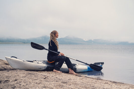 Woman sitting on kayak on the shore of mountain lake