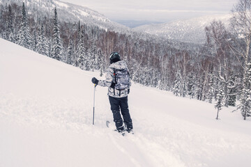 Woman skier standing on  hillside enjoying silence and freedom of the moment