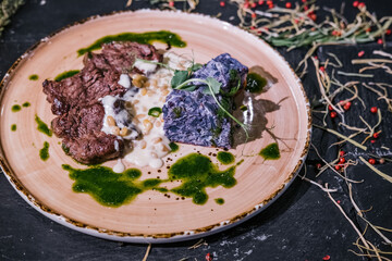 Meat medallions with cedar porridge and red cabbage gratin on a large plate
