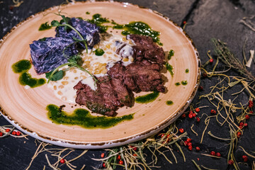 Meat medallions with cedar porridge and red cabbage gratin on a large plate