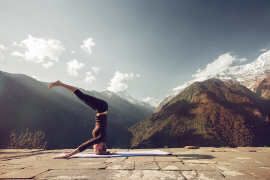 Beautiful yoga picture in magnificent mountain scenery on  sunny day. Yoga outdoor. Young female doing headstand