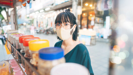 Happy young adult asian foodie woman order vendor asia dessert. Wear face mask looking at camera....