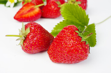 Ripe strawberries with leaves and flowers on a white background.