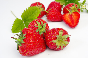 Ripe strawberries with leaves and flowers on a white background.