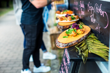 Ordering street food at food truck. Spicy chicken wings with vegetable and herbs