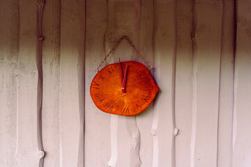 stylized wooden clock on the chain on the wooden wall