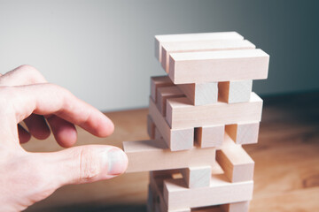 Closeup of a businessman making a structure with wooden cubes. Building a business concept.