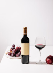 Glass of red wine with grapes and apples on white table