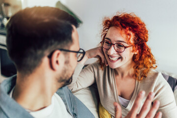 Young happy couple having fun while talking about something funny at home