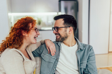 Young happy couple having fun while talking about something funny at home