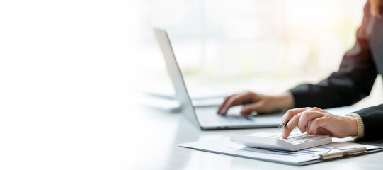 businesswoman working at office with document on her desk, finance analysis concept. Using calculator and tablet.