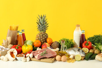 Grocery on white table against yellow background