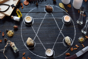 Pentagram circle with candles, stones, love potion and old books on witch table. Occult, esoteric...