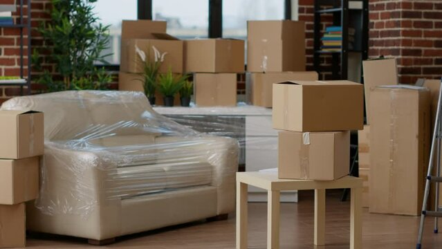 No people in empty living room apartment with carton boxes on stack, moving cardboard storage packaging in new household. Nobody in relocation property with interior furniture cargo.