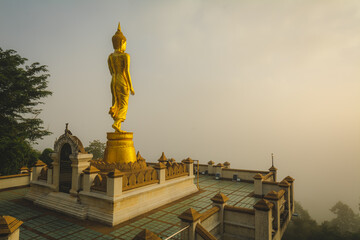 Fototapeta na wymiar Golden Buddha statue in the morning at Wat Phra That Khao Noi, or Phrathat Khao Noi temple, is the top attraction with a fantastic view of Nan province, Thailand