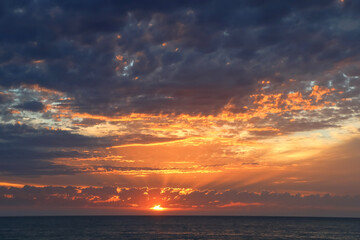 Seascape, sunset over the sea, the sun s rays break through the clouds, dramatic sky 