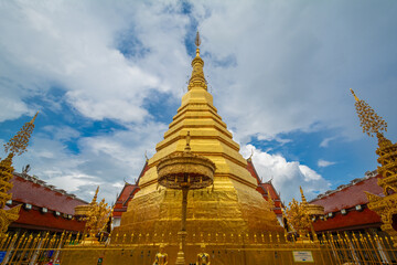Naklejka premium The gold pagoda in Wat Phrathat Cho Hae, Phrae province, Thailand. This gold pagoda is famous and was built on a mountain.