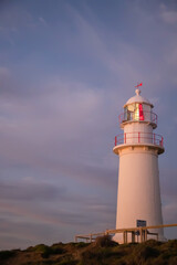 White lighthouse with red elements against the backdrop of the dark blue sunset sky, close up