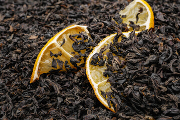 Closeup view on black dry loose tea with dry lemon slices