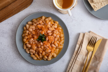Stewed beans with vegetables in spicy tomato sauce on a plate top view