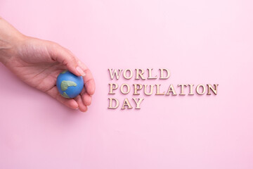 World population day write by wooden letter with globe in woman hand