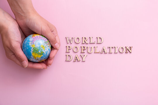 World population day write by wooden letter with globe in woman hands