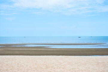 Yellow warm sand and summer sea with sky at coast beautiful outdoor nature landscape in the morning with a fishing boat.