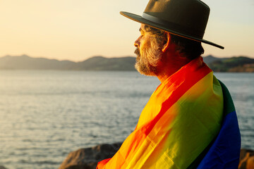 Portrait of a man with an lgtbi pride flag in the light of sunrise