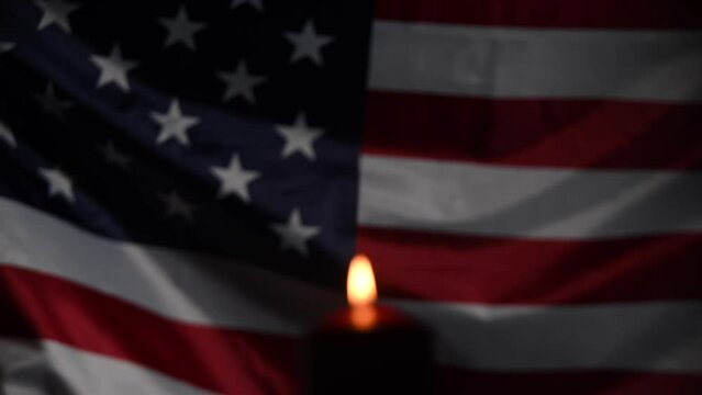 Burning candle against the background of the waving flag of the united states of america in the dark.
