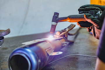 Closeup welding motorcycle frame in workshop, bike silencer
